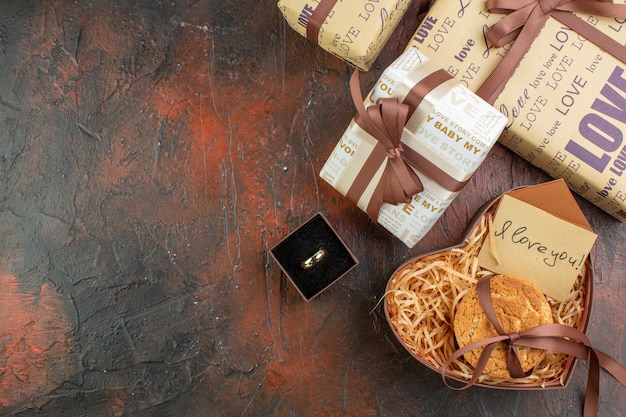 Vista dall'alto regali di San Valentino con anello e biscotti sullo sfondo marrone scuro amore coppia colore regalo sensazione matrimonio vacanza