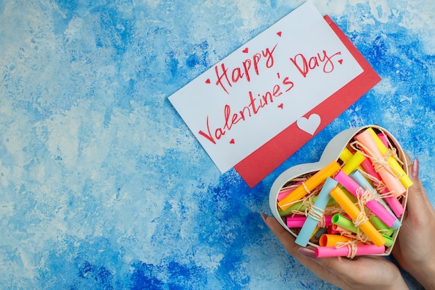 vista dall'alto scatola a forma di cuore con cartoncini a scorrimento in mani femminili buon san valentino scritto su lettera su sfondo blu copia posto