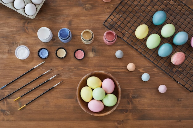 Vista dall'alto sfondo di uova di Pasqua color pastello su tavola di legno e forniture artistiche, decorazioni pasquali fai da te, spazio copia