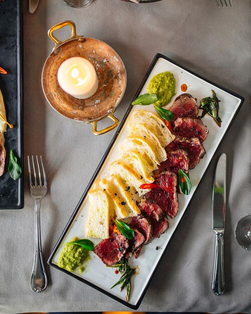 Vista dall'alto su antipasto di roast beef con pane sul tavolo servito