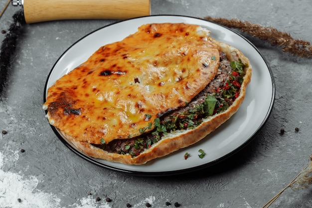 Vista dall'alto sul khachapuri georgiano con agnello e peperoncino sul tavolo di legno.