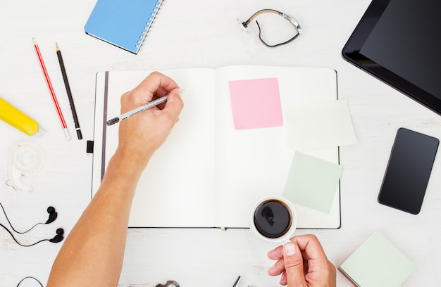 Vista dall'alto sul posto di lavoro Uomo che lavora con dispositivi moderni e scrive su notebook