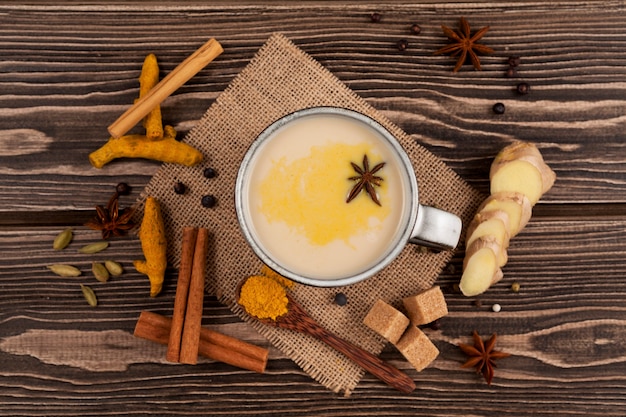 Vista dall'alto sulla bevanda indiana tradizionale masala chai, tè con latte e spezie sulla tavola di legno.