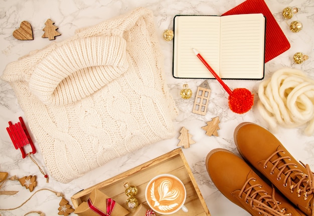 Vista dall'alto sulla composizione di Natale con maglione caldo, regali, luci di Natale e caffè