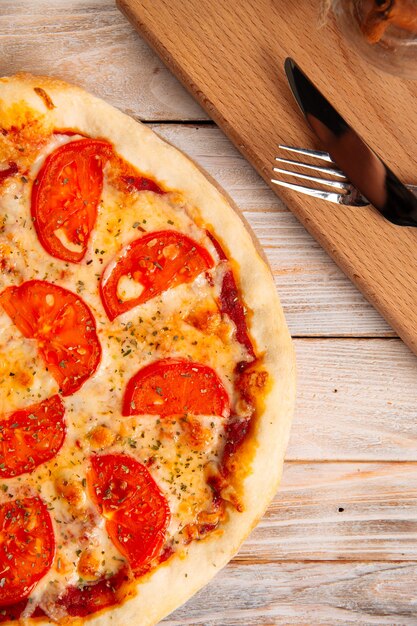 Vista dall'alto sulla pizza con i pomodori sul tavolo di legno