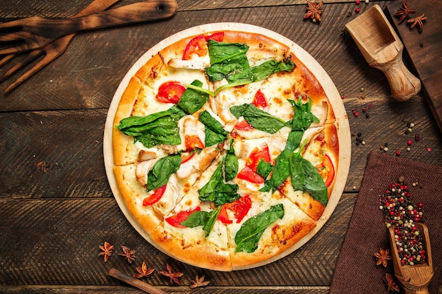 Vista dall'alto sulla pizza napoli con spinaci e pomodori sul tavolo di legno