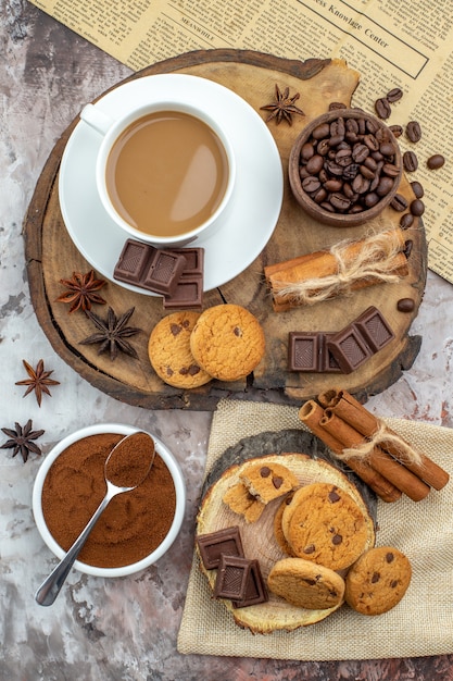 vista dall'alto tazza di caffè biscotti ciotola con chicchi di caffè cioccolato bastoncini di cannella anice stelle su tavola di legno ciotola di cacao sul tavolo