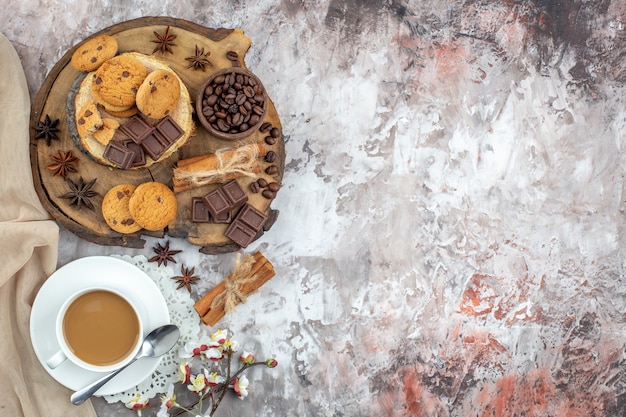 vista dall'alto tazza di caffè ciotola con chicchi di caffè tostati e cacao cioccolato bastoncini di cannella biscotti su tavola di legno sul tavolo con spazio libero