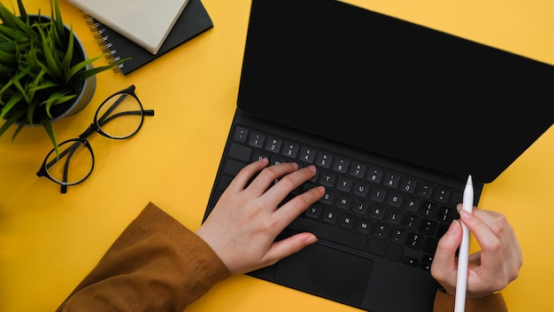 Vista dall'alto Una donna creativa che lavora sul suo tablet sulla scrivania gialla dell'ufficio