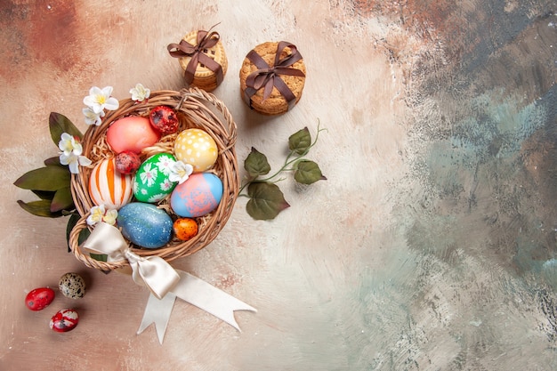 vista dall'alto uova di Pasqua colorate all'interno del cesto sulla superficie chiara