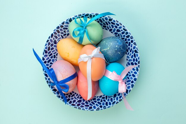 vista dall'alto uova di Pasqua colorate all'interno del piatto su superficie blu