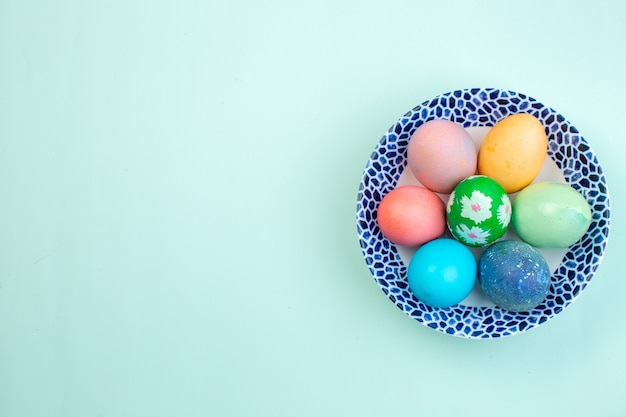 vista dall'alto uova di Pasqua colorate all'interno del piatto su superficie blu