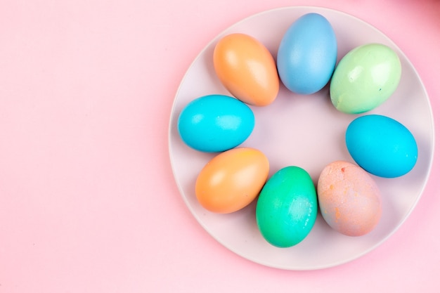 vista dall'alto uova di Pasqua colorate all'interno del piatto su superficie rosa