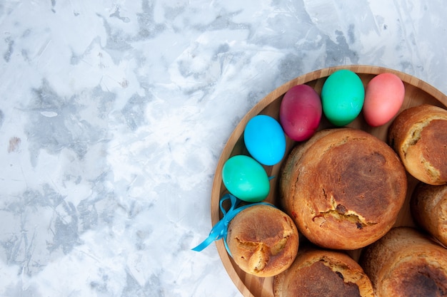 vista dall'alto uova di pasqua colorate con pane e torte per le vacanze all'interno del vassoio su superficie bianca