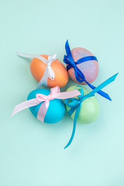 vista dall'alto uova di Pasqua colorate legate con graziosi fiocchi su superficie blu