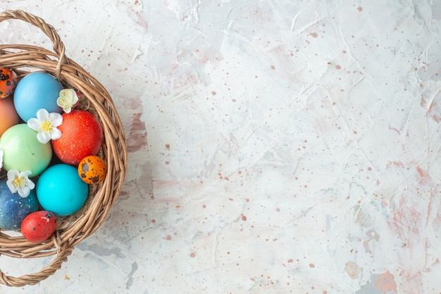 Vista dall'alto uova dipinte colorate all'interno del cestello su sfondo bianco novruz ornato primavera colorato concetto di vacanza orizzontale spazio libero
