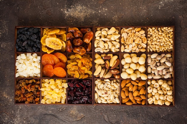 Vista dall'alto varietà di noci e frutta secca e candita in scatole di legno su fondo di cemento marrone