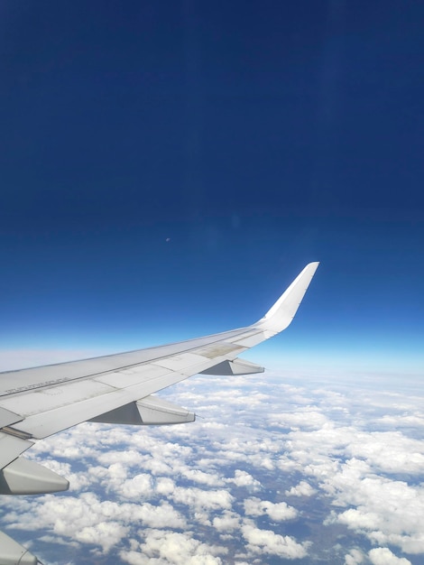 Vista dalla finestra dell'ala di un aeroplano che vola alto sopra un cielo blu Puoi vedere i coludi e le città sotto di noi