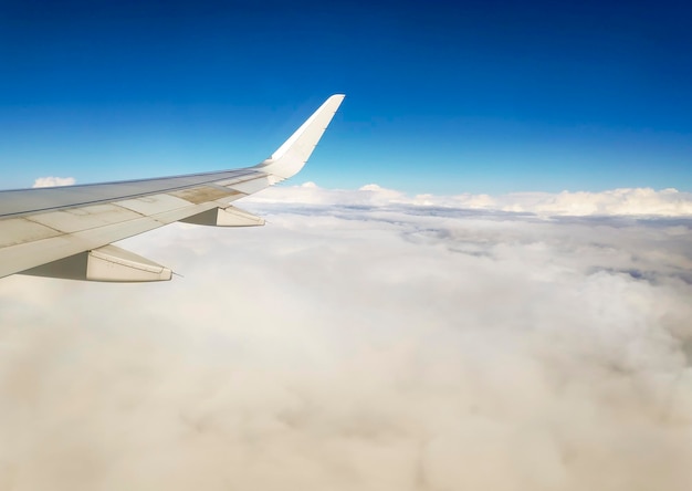 Vista dalla finestra dell'ala di un aeroplano che vola sopra le nuvole e un cielo blu