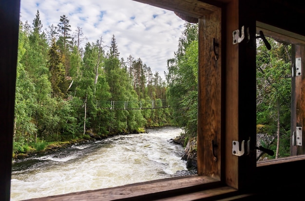 Vista dalla finestra di un vecchio mulino su un ponte sospeso, Finlandia. Parco Nazionale di Oulanka