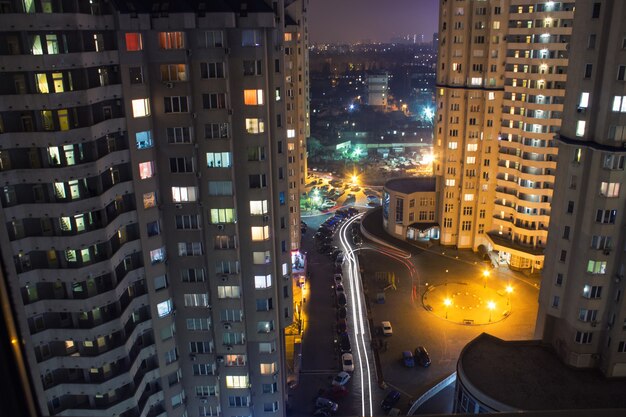 Vista dalla finestra grattacieli di notte con illuminazione e auto in movimento con luce sfocata