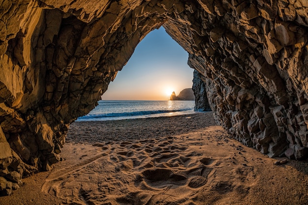 Vista dalla grotta di pietra sul mare al tramonto e sulla spiaggia