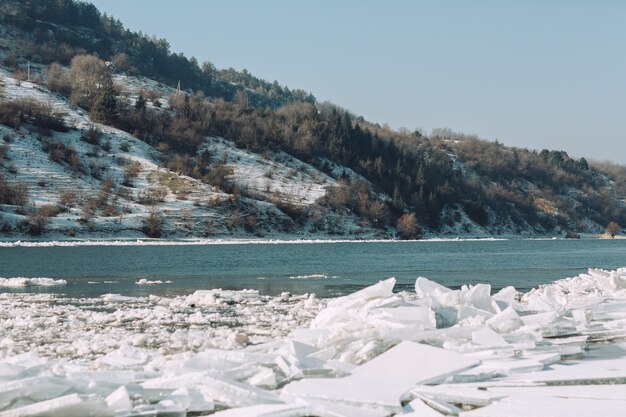 Vista dalla riva del fiume sui banchi di ghiaccio, colline innevate e acqua blu nella giornata di sole