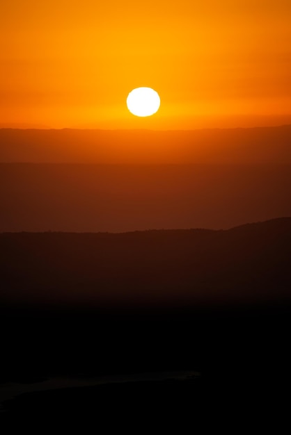 Vista degli strati delle creste delle montagne con il sole bianco al tramonto a Cordoba Argentina Immagine verticale