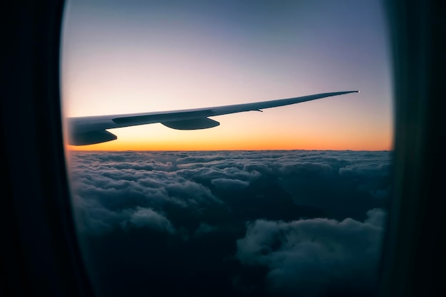 Vista del bellissimo tramonto sulle nuvole dal finestrino dell'aereo durante il volo Dentro la cabina Alba a diecimila metri di altitudine