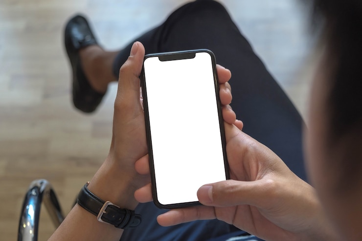 Foto vista del colpo ritagliata delle mani dell'uomo che tiene il telefono astuto con lo schermo in bianco dello spazio della copia per il messaggio di testo o il contenuto informativo femminile che legge il messaggio di testo sul telefono cellulare durante l'ambiente urbano.