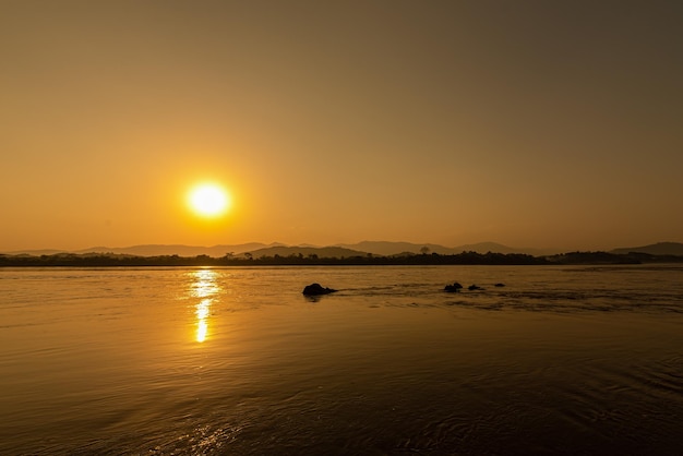 Vista del fiume Mekong al mattino circondato da montagne e raggi di sole gialli al tramonto