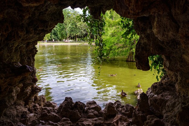 Vista del lago con anatre e vegetazione da una grotta di roccia. Il Retiro Madrid.