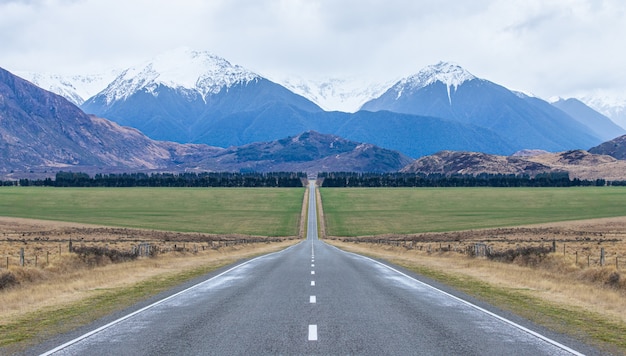 vista del lungo rettilineo strada ghiacciata che porta verso le montagne isola del sud della Nuova Zelanda