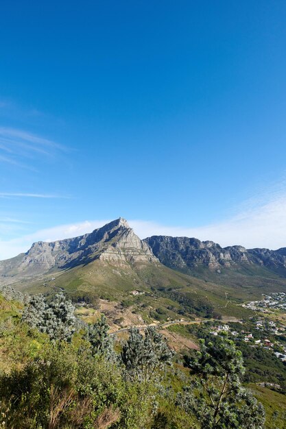 Vista del paesaggio delle montagne sullo sfondo di un lussureggiante giardino botanico verde e del parco nazionale Table Mountain a Città del Capo in Sud Africa con cielo blu e spazio per la copia mentre si scopre la pace nella natura