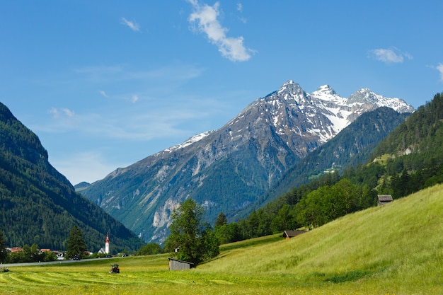 Vista del paese di montagna alpina estiva con prato erboso e strada per il villaggio (Austria)