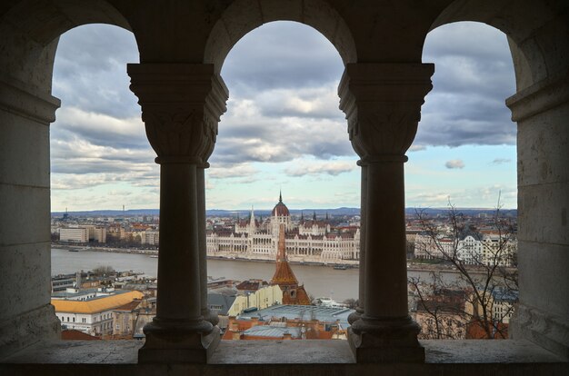 Vista del parlamento di Budapest da dietro alcune colonne sul fiume.