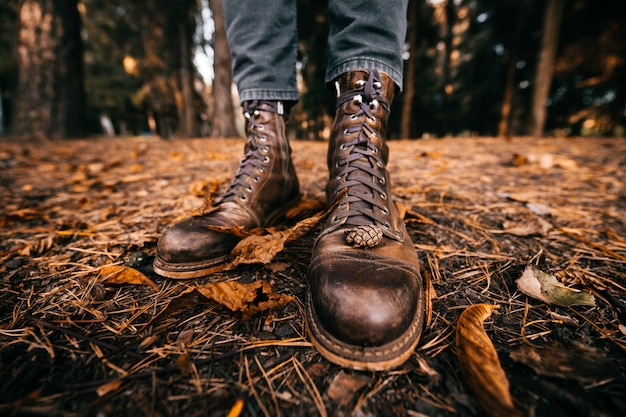 vista del primo piano alle gambe maschili in stivali di pelle vintage nel parco in autunno