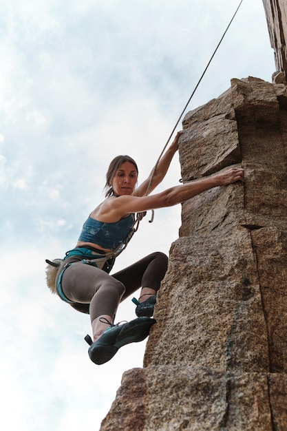 Vista del primo piano da sotto di una giovane donna un atleta che sta arrampicandosi su una roccia nella natura i