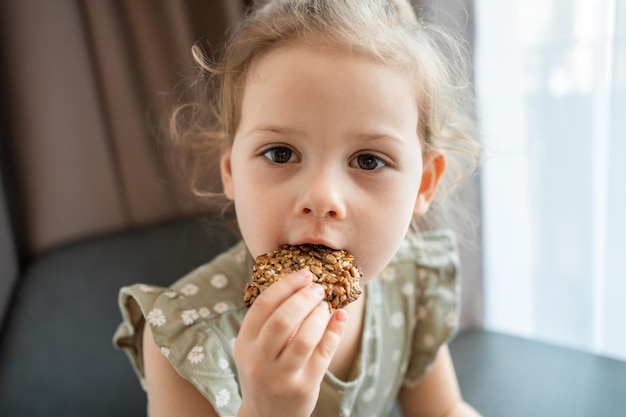 Vista del primo piano del pezzo di biscotti con banana e semi in mano della bambina