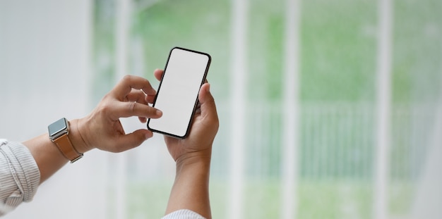 Vista del primo piano dell'uomo che tiene lo smartphone dello schermo in bianco