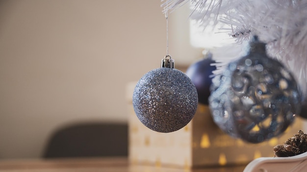 Vista del primo piano delle bagattelle blu lucide di festa che appendono su un ramo più basso dell'albero di Natale