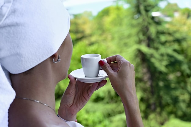 Vista del retro di una bella donna rilassante di lusso che gode di una tazza di tè al caffè su uno sfondo all'aperto del mare del cielo blu