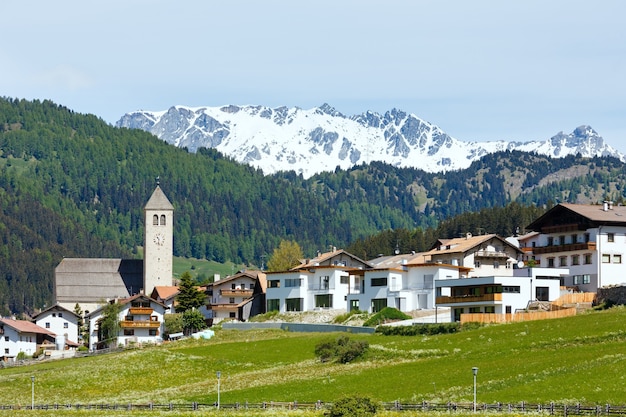 Vista del villaggio di montagna alpino estivo con prato erboso (Italia)