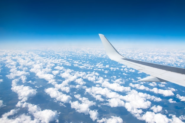 Vista dell'ala dell'aeroplano su un winglets e motore a reazione, soffici nuvole sullo skyline durante la scalata del livello di volo.
