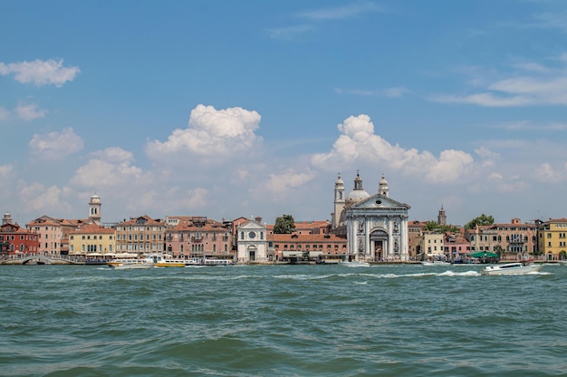 Vista dell'argine del Canale di Venezia in una calda giornata estiva, con barche galleggianti e vecchie case, Venezia
