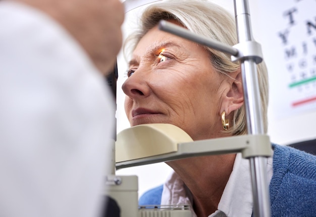 Vista dell'esame oculistico o test laser per una donna con una macchina alla consultazione di optometria per problemi alla retina Paziente anziano o cliente maturo con assicurazione sanitaria medica che controlla la vista all'ottico