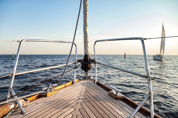 Vista della barca a vela di prua contro il cielo con nubi cumuliformi nell'oceano Colpo grandangolare dello yacht anteriore con corde sullo sfondo dell'orizzonte del mare