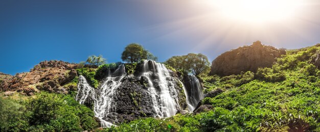 Vista della bellissima cascata di montagna con cielo nuvoloso blu sullo sfondo