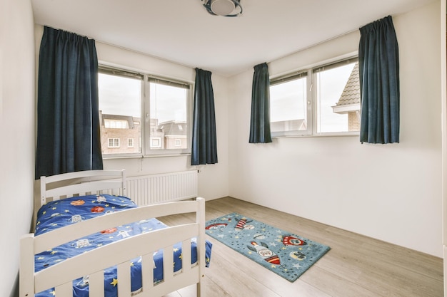 Vista della camera da letto minimale con letto a due finestre, moquette blu e pavimento in parquet