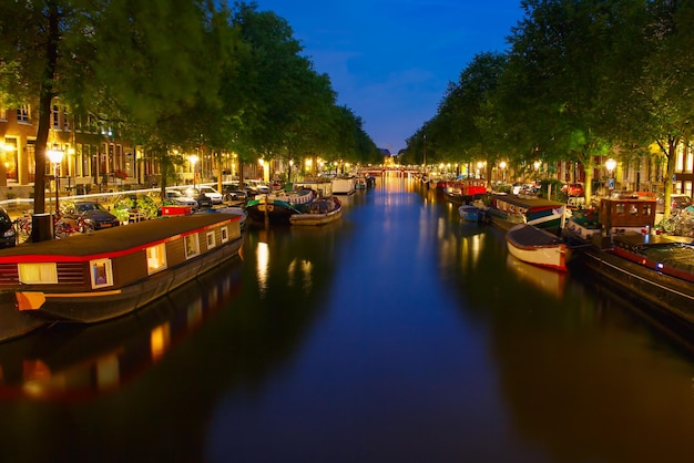 Vista della città di notte del canale di Amsterdam e della casa galleggiante tipica, Olanda, Paesi Bassi.